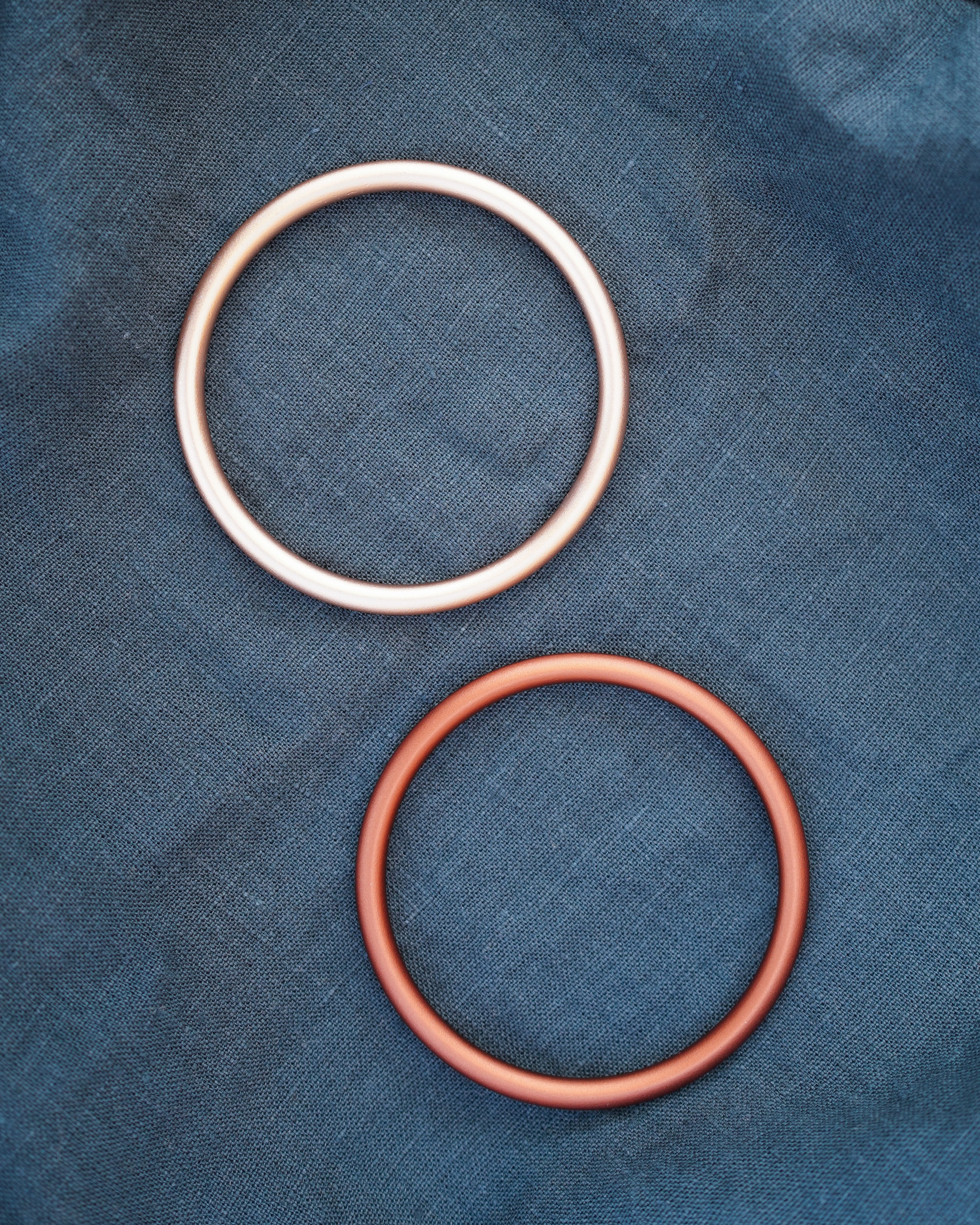 Ringe in gold und bronze auf einem blau-grünem Leinenstoff.