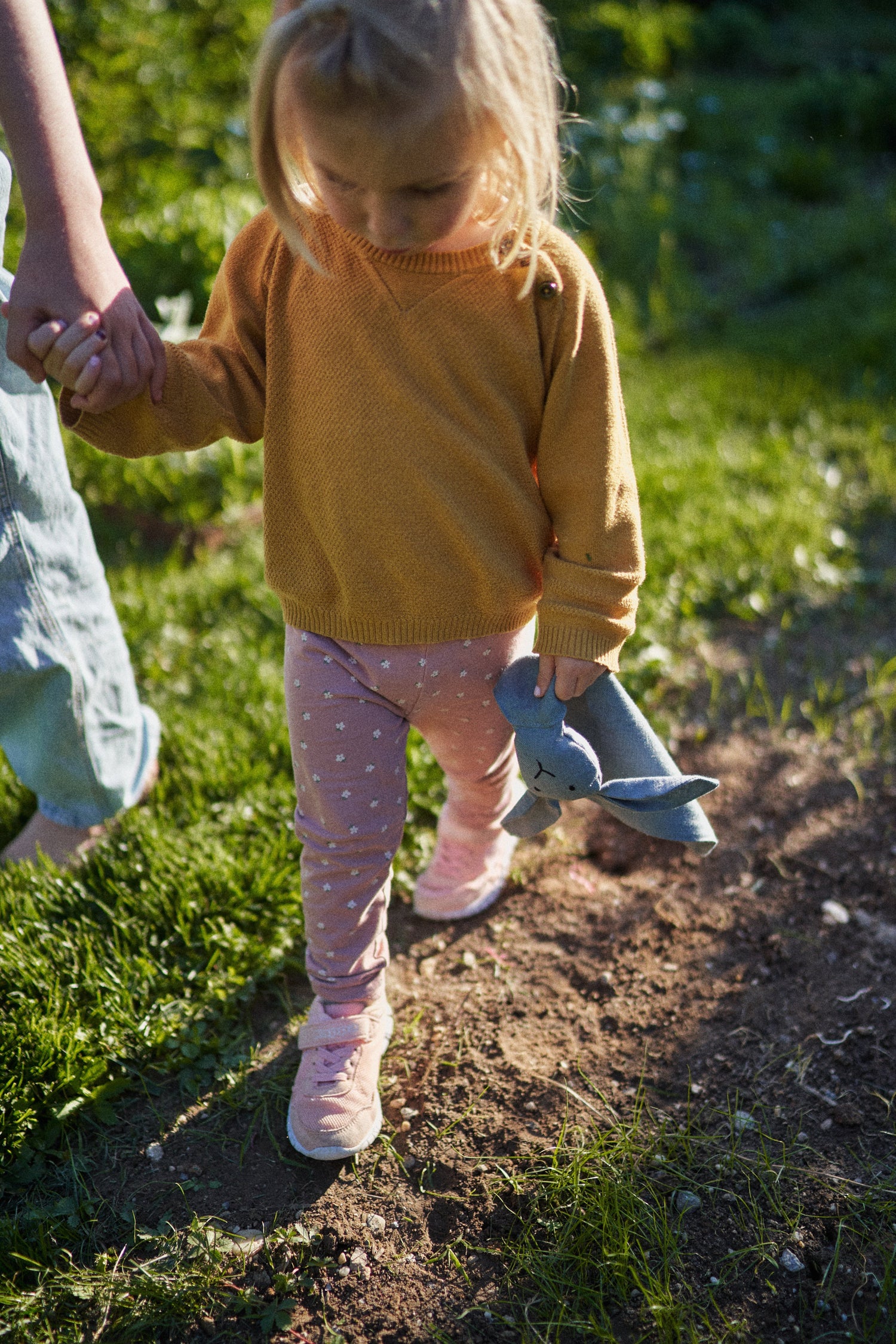 Mädchen geht friedlich mit ihrem Kuschelhasen an der Hand