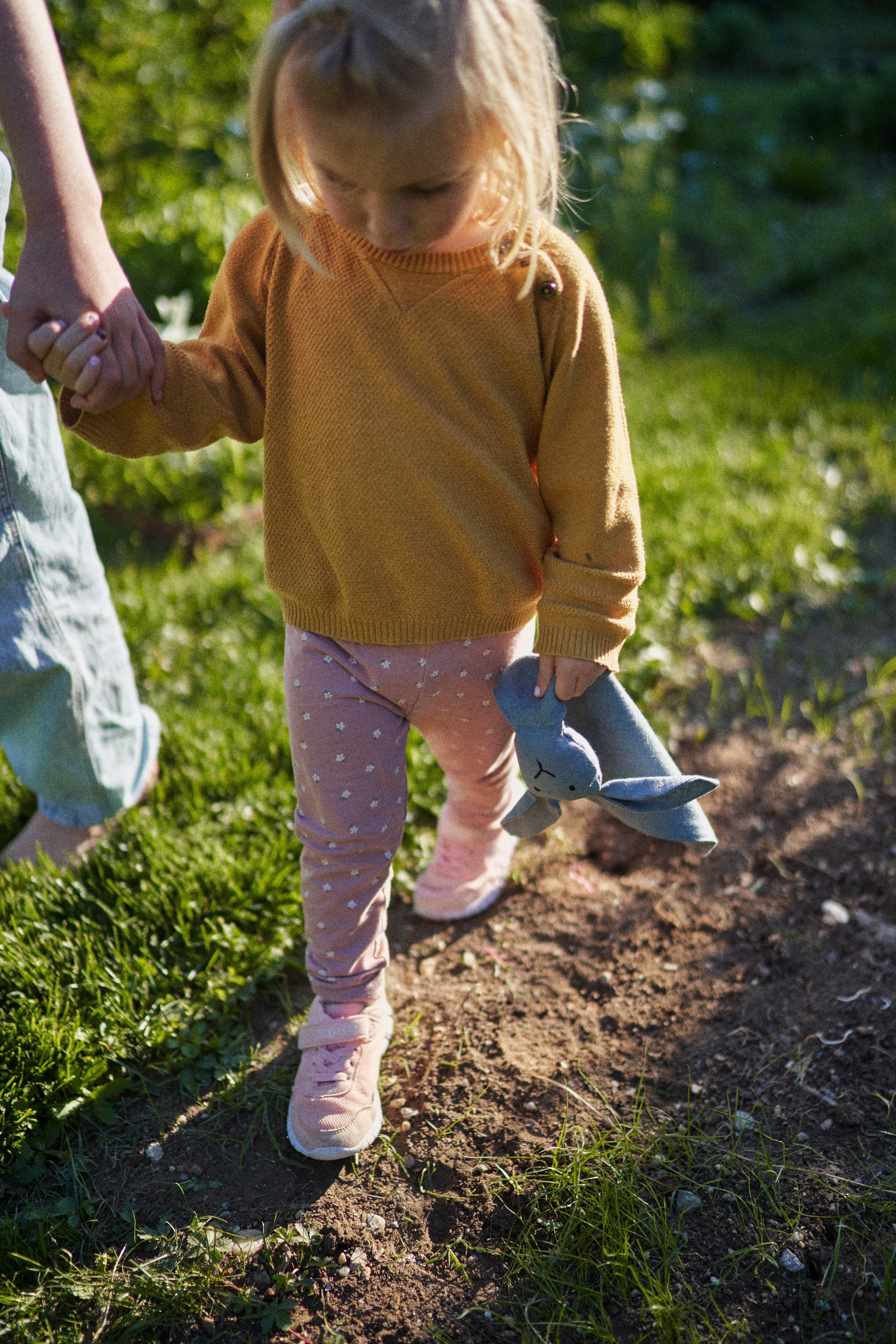 Mädchen geht friedlich mit ihrem Kuschelhasen an der Hand